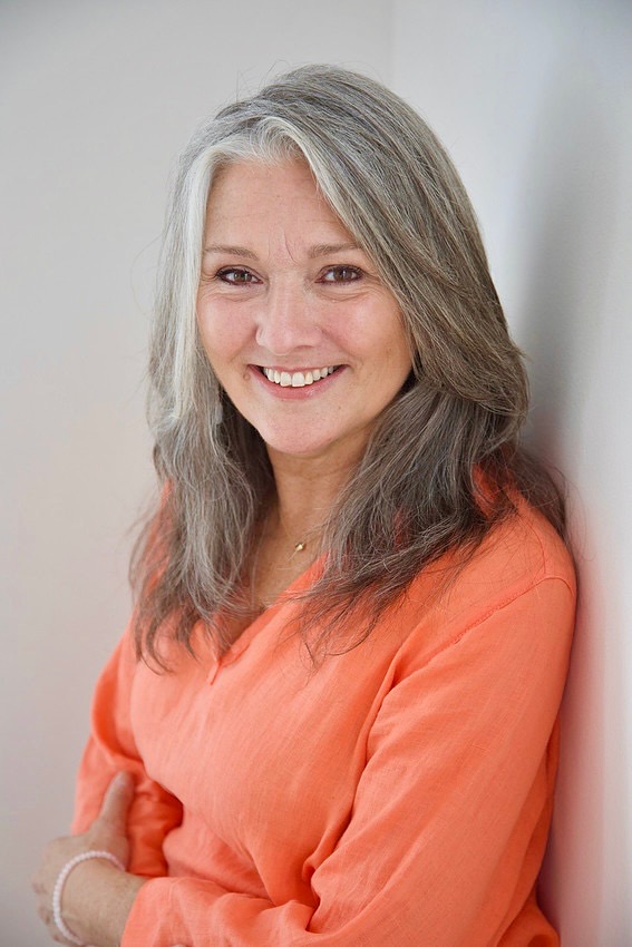 Founder of Sanctuary Space smiling in a coral blouse against a soft neutral wall